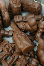 Load image into Gallery viewer, 2. “Detail van chocoladefiguurtjes met Sinterklaas, een kat, sint en een locomotief, liggend bij elkaar.”