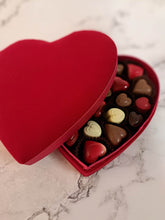 Load image into Gallery viewer, Close-up van luxe ambachtelijke pralines: vanille, praliné, framboos en koffie, in fluwelen hartvormige doos – online te bestellen